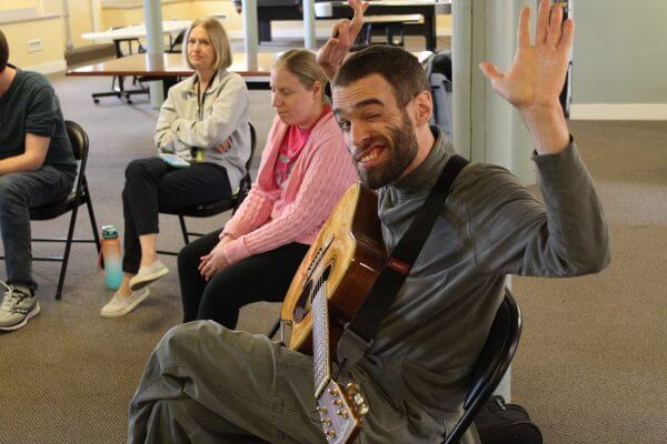 A resident playing guitar in a music class
