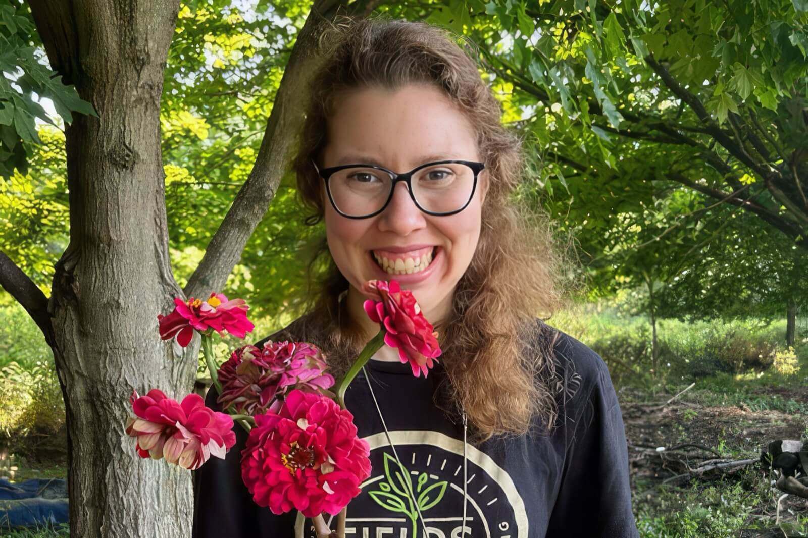 A Village of Merici resident smiling outdoors, holding a bundle of cut flowers from the garden