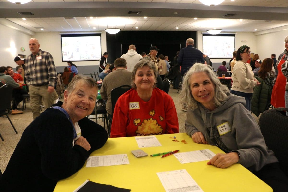 Three players smiling at a card table at the 2026 Euchre Tournament