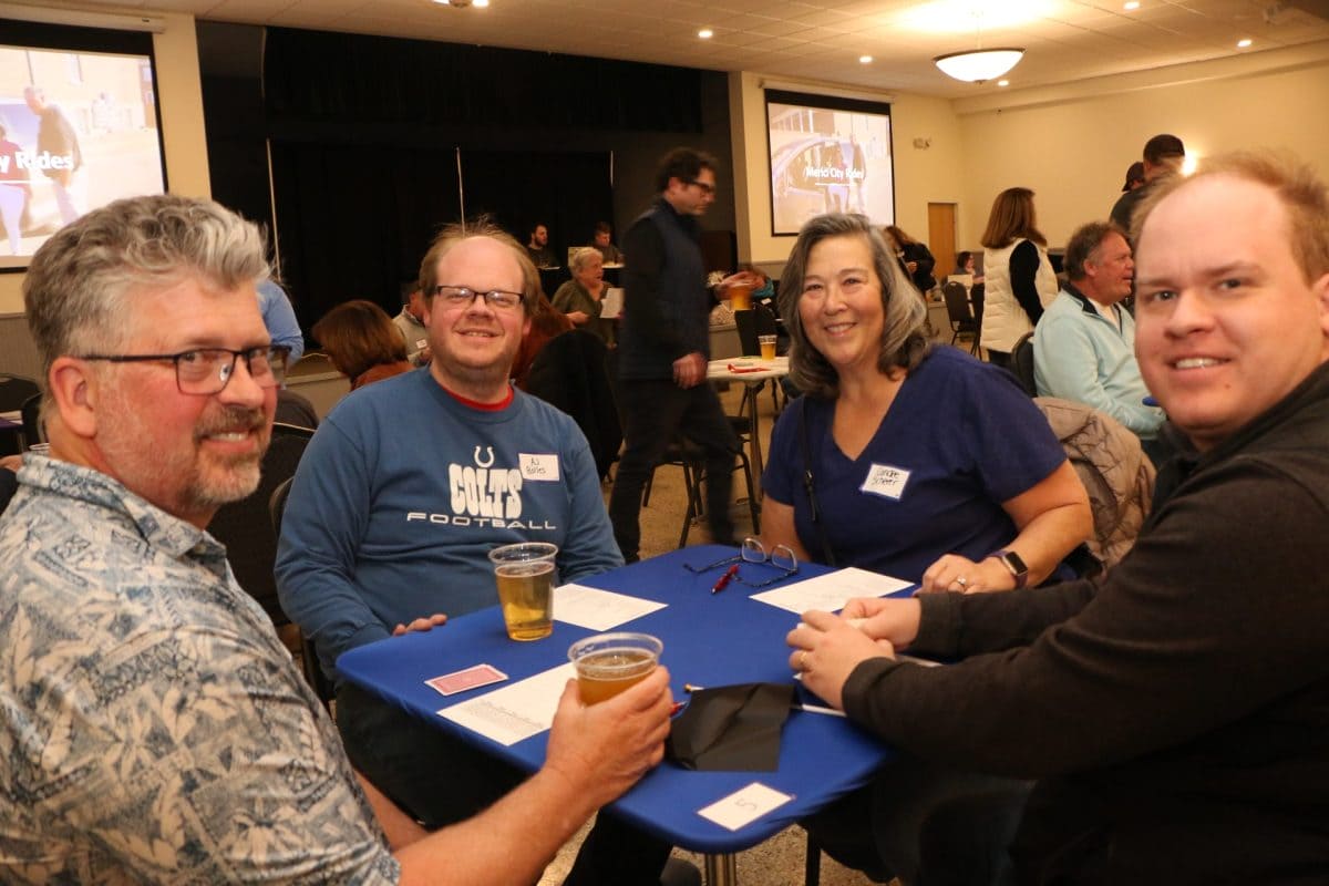 Players at a card table smile for the camera