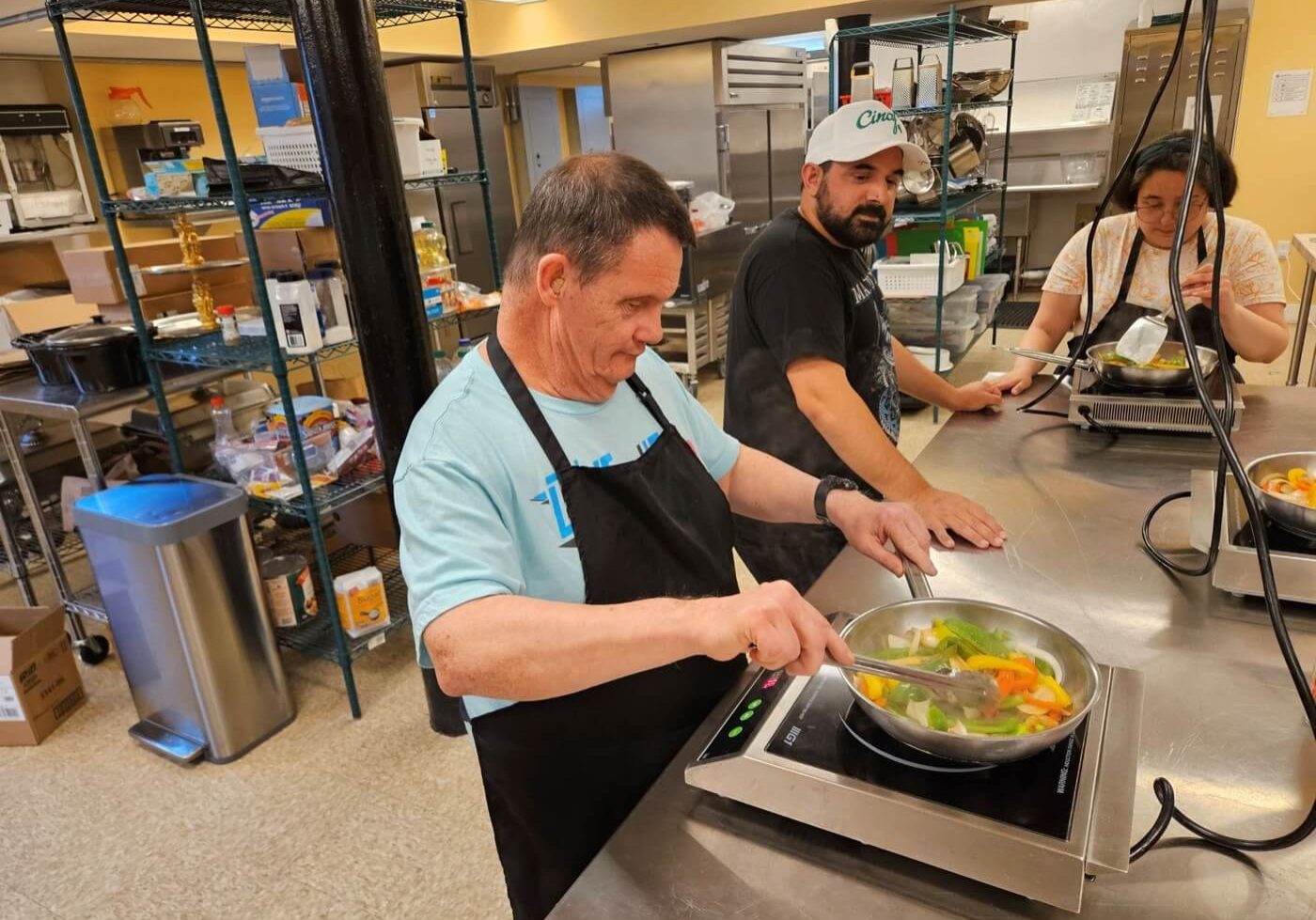 A Village of Merici coach and a person we support cooking together in the kitchen