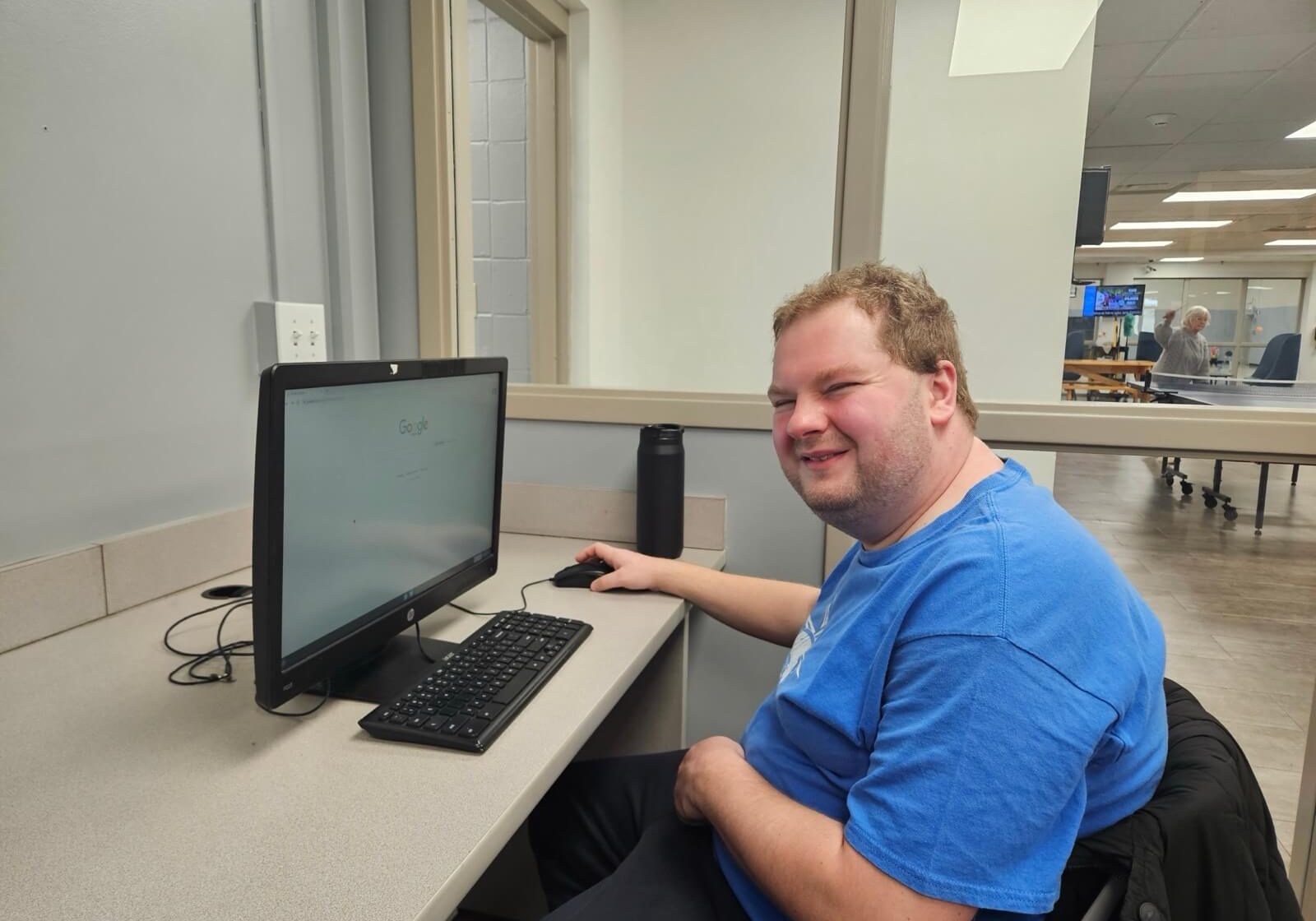 A resident smiling at a computer station in a community room